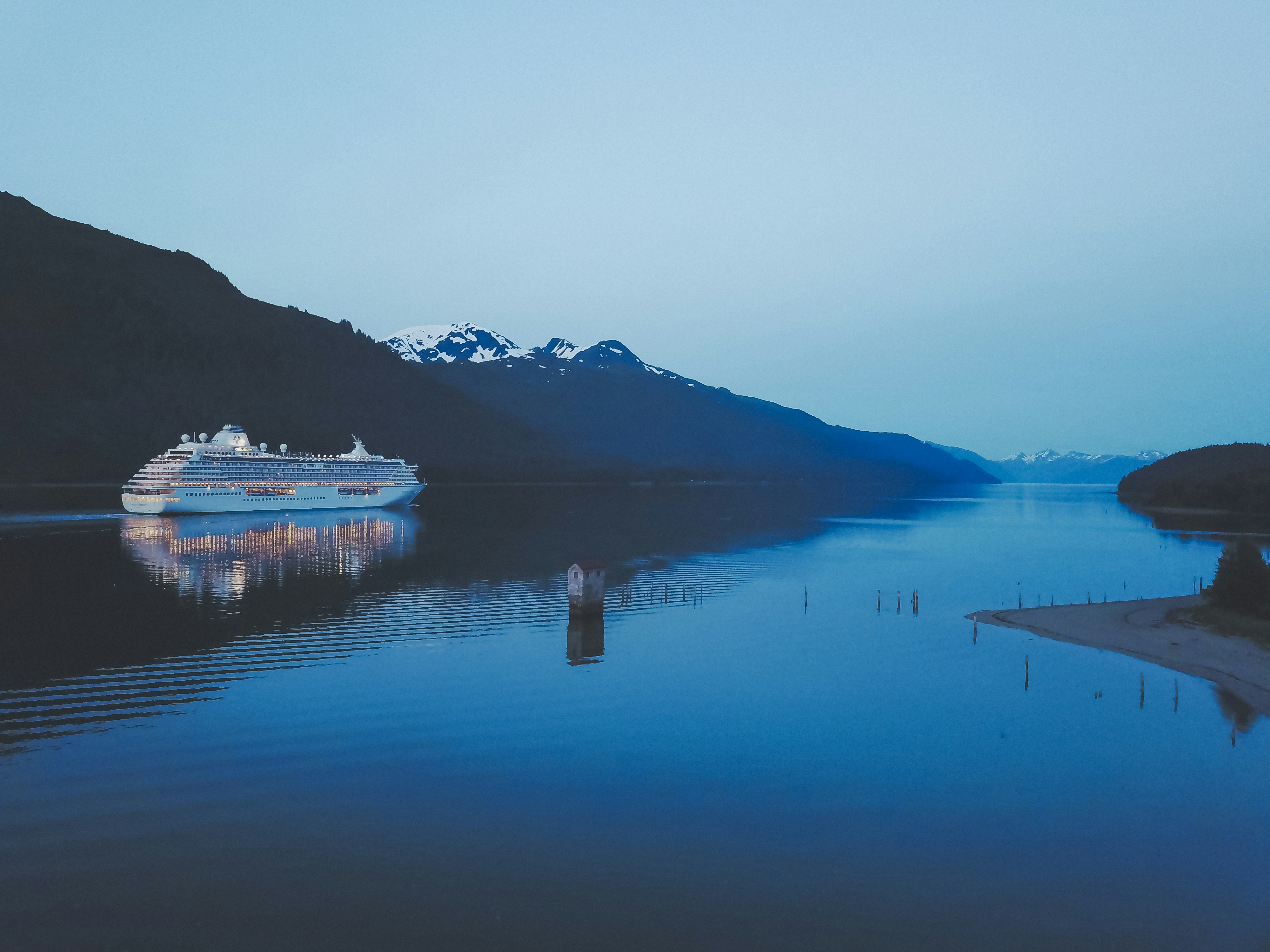 Cruise ship sailing at dusk through mountain fjord